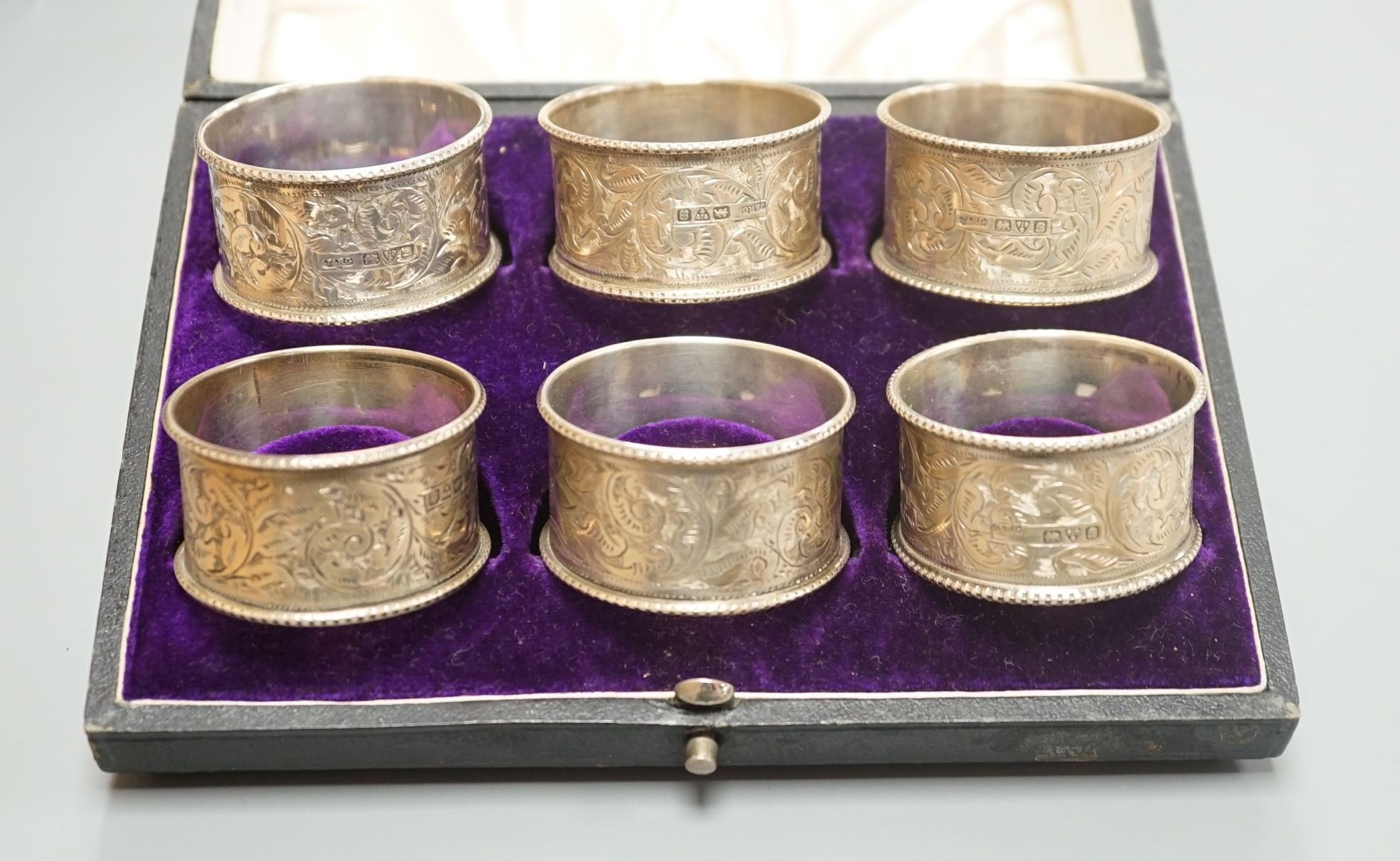 A cased set of six Edwardian engraved silver napkin rings, J & R Griffin, Chester, 1902.